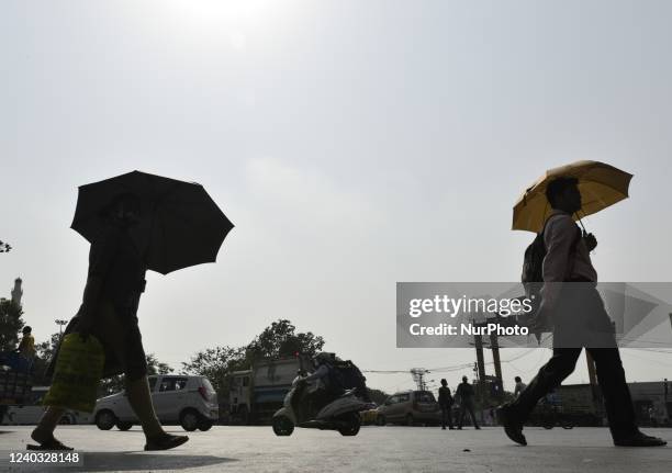 People carry umbrella amid heatwave in Kolkata, India, 29 April, 2022.