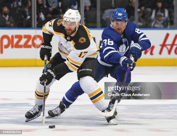 Nick Foligno of the Boston Bruins skates with the puck against a checking William Nylander of the Toronto Maple Leafs during an NHL game at...