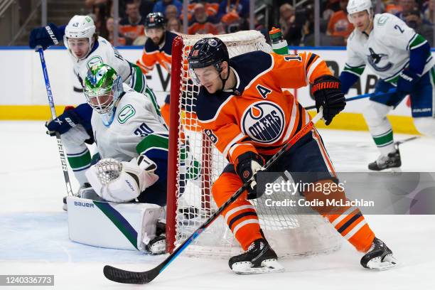 Zach Hyman of the Edmonton Oilers brings the puck around the net as goaltender Spencer Martin of the Vancouver Canucks defends the short side during...