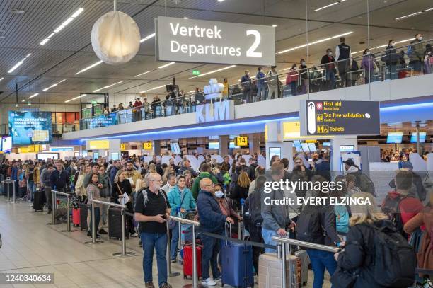 Passengers wait in line at the Schiphol Airport, on April 30, 2022. - The airport is facing serious staff shortages due to hundreds of vacancies at...