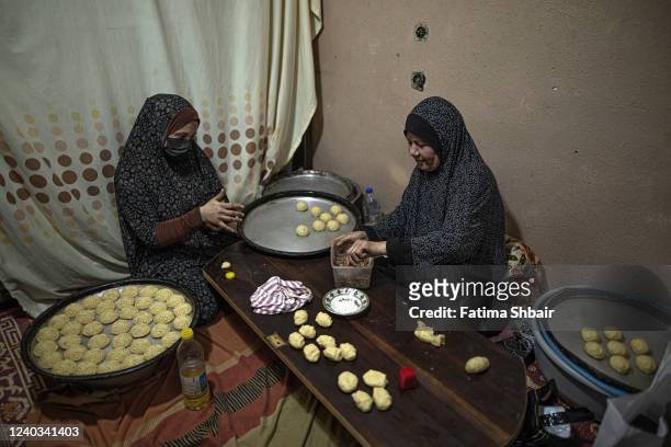 Palestinian women make traditional date-filled cookies in preparation for the Eid al-Fitr holiday at their shop in the old Gaza city on April 29,...