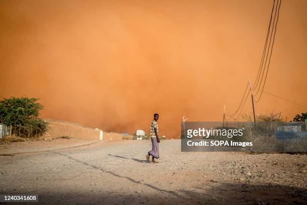 Man walks in front of a sandstorm in Dollow, southwest Somalia. People from across Gedo in Somalia have been displaced due to drought conditions and...