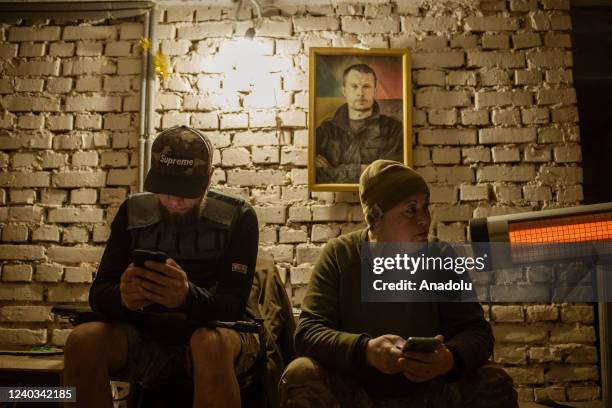 Stanislav Lopatskyi and nurse Tanya sit in a bunker next to the portrait of the founder of the Azov battalion, Andriy Biletsky at the center of Azov...