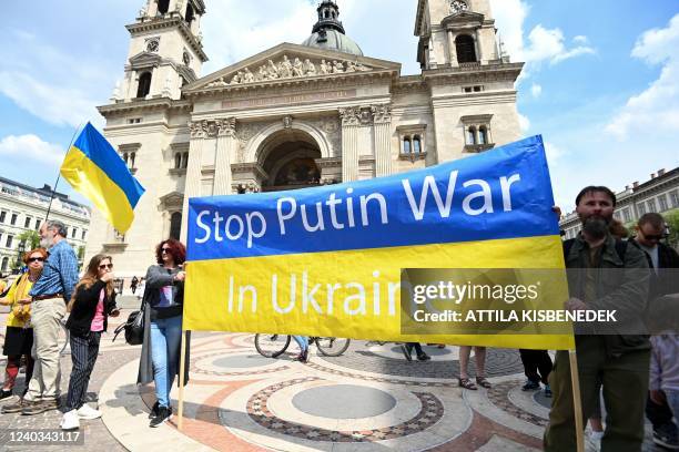 Participants stand with a Ukrainian flag and the lettering 'Stop Putin War in Ukraine' during a protest against Russia's aggression and war in...