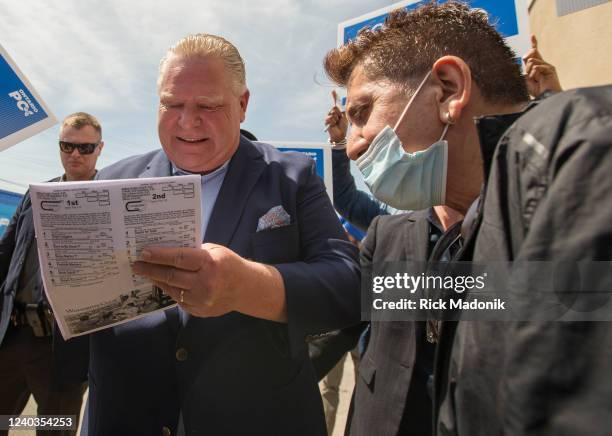 Ontario PC Leader Doug Ford signs his autograph on a racetrack booklet. Ford showed off the campaign bus at a stop at his Etobicoke campaign office....