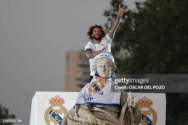 Real Madrid's Brazilian defender Marcelo gestures on top of a statue on the Plaza Cibeles square in Madrid, after Real Madrid CF won the Spanish...