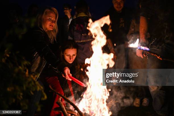 People wear flower crowns and hold candles as they stand around a fireplace during the Beltane celebrations in Krakow, Poland on April 30, 2022....