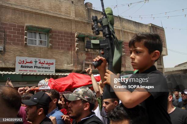 Kid holds a riffle next to the carried body of 27-year-old Palestinian Yahya Badwan in the town of Azzun in the northern occupied West Bank, who was...