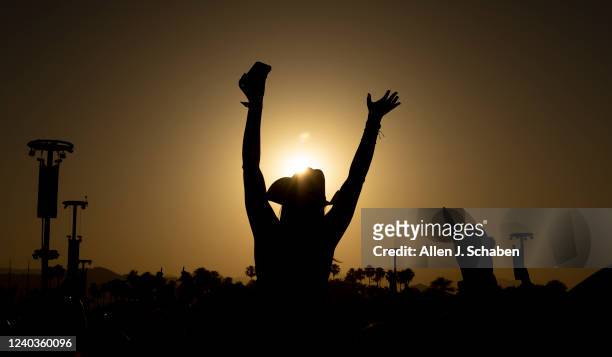 Fan hoisted up high above the crowd is silhouetted at sunset while cheering for Midlands performance on the Mane Stage on the first day of the...