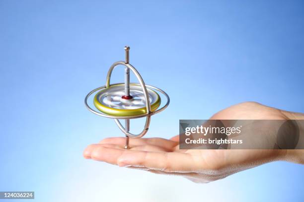 spinning gyroscope in hand - gyroscope stock pictures, royalty-free photos & images