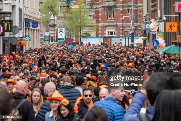 Crowds of people wearing mainly orange clothes and having the Dutch flag as seen in the streets of Amsterdam while The Netherlands celebrates King's...