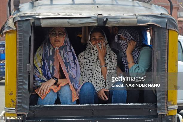 Women cover their faces with cloth while travelling in an autorickshaw on a hot summer day in Amritsar on May 1, 2022.