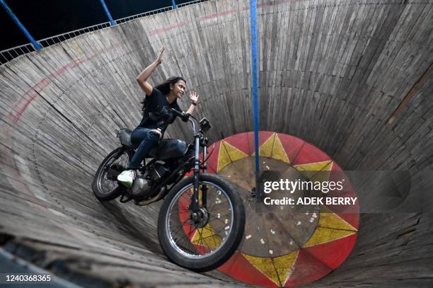 This photo taken on April 30, 2022 shows daredevil Karmila Purba, a rider of the "wall of death", locally known as a "Tong Setan", performing inside...