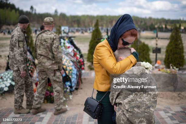 Alla hugs her son Savelii near the grave of Ihor Krotkih, husband of Alla and father to Savelii, as Ukrainian soldiers pay respects to their fallen...