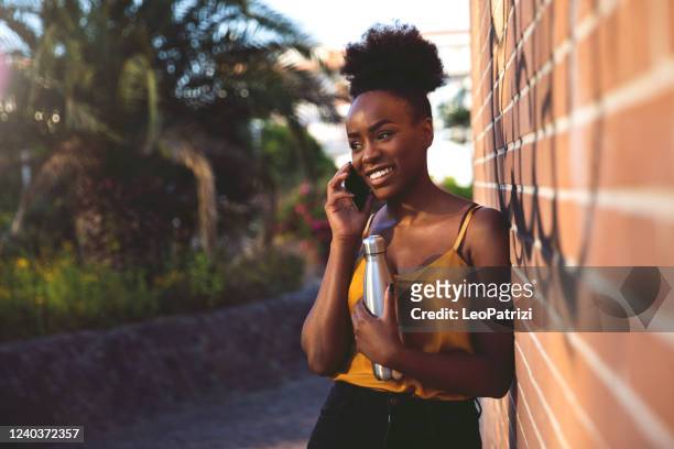 garota millennial mandando sms no celular novamente uma parede de tijolos no parque - reusable water bottle - fotografias e filmes do acervo