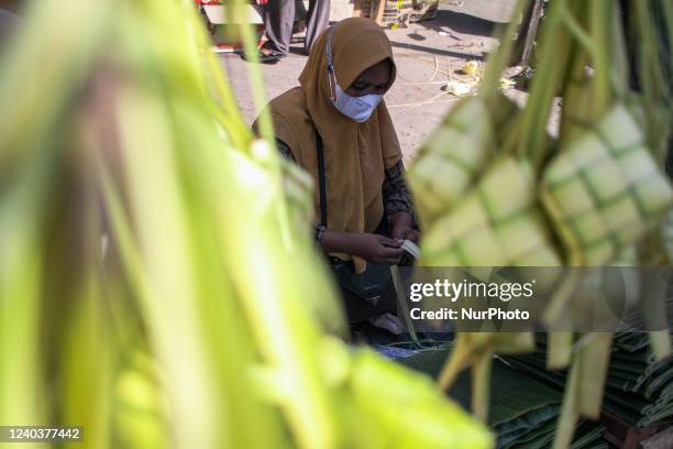 Trader weaves coconut leaves used to make traditional rice cakes called 'Ketupat' preparations ahead of Eid al-Fitr, at a traditional market in...