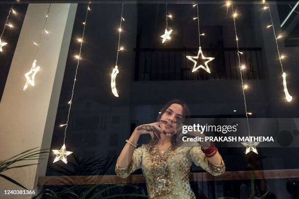 Woman pose for pictures after applying henna tattoos on her hands during 'Chand Raat' or 'Night of the Moon' in Kathmandu on May 1 on the eve of the...