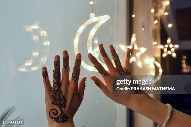 Woman pose for pictures after applying henna tattoos on her hands during 'Chand Raat' or 'Night of the Moon' in Kathmandu on May 1 on the eve of the...