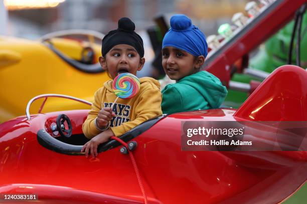 Child eats a lollipop on a carnival ride during an Eid fair in Goodmayes Park on May 1, 2022 in Ilford, England. The fair was held to mark the end of...