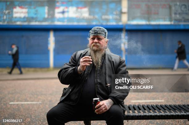 Man smokes a cigarette, sitting on a bench in Dudley town centre in central England on April 29, 2022. - Rampant inflation and lockdown-breaking...