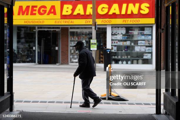 Pedestrian walks past a High street store in Dudley, central England on April 29, 2022. - Rampant inflation and lockdown-breaking parties are...