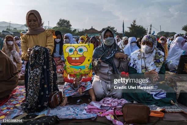 Girl holds a balloon as muslims women attend the Eid Al-Fitr prayer on the 'sea of sands' at Parangkusumo beach on May 02, 2022 in Yogyakarta,...