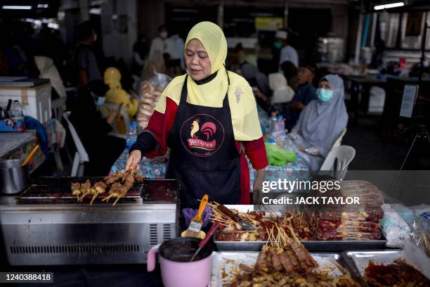 Woman grills halal meat following morning prayers at The Foundation of the Islamic Centre of Thailand mosque during Eid al-Fitr celebrations, marking...