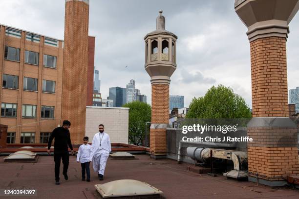 Two men and a boy walk across the roof top of East London Mosque before morning prayers during Eid Al-Fitr celebrations on May 2, 2022 in London,...