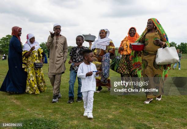 Family carries pots of food during Eid Al-Fitr celebrations at Burgess Park on May 2, 2022 in London, England. Eid al-Fitr comes at the end of...
