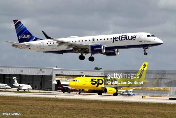 JetBlue airliner lands past a Spirit Airlines jet on taxi way at Fort Lauderdale Hollywood International Airport on Monday, April 25, 2022.