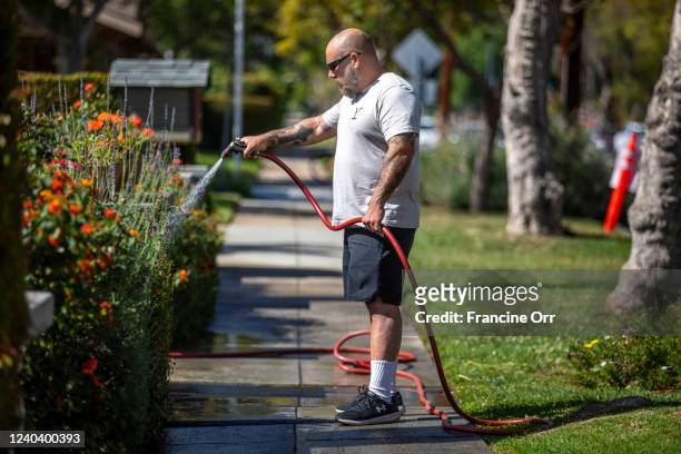 Scott Moses waters flowers in his front yard in South Pasadena at on Saturday, April 30, 2022.