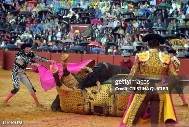 The bull knocks down the picador's horse during the Feria de Abril bullfighting festival at La Maestranza bullring in Seville on May 2, 2022.