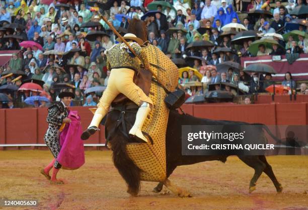 The bull charges the picador's horse during the Feria de Abril bullfighting festival at La Maestranza bullring in Seville on May 2, 2022.