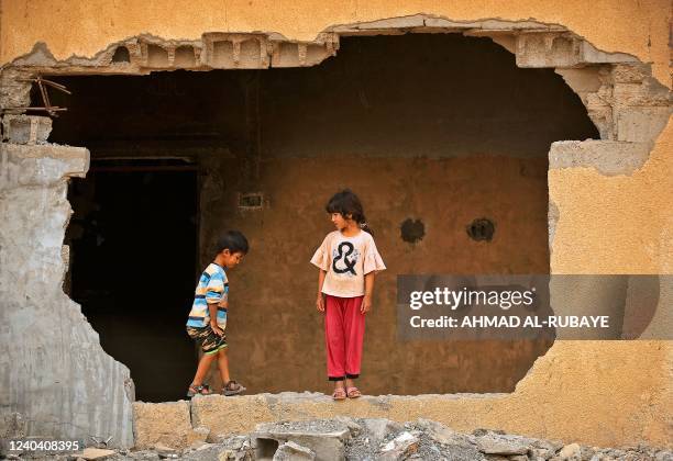 Children play outside their damaged house in the war-ravaged village of Habash, some 180 kilometres north of Iraq's capital Baghdad, on April 25,...