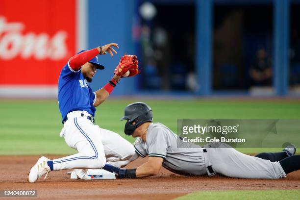 Aaron Judge of the New York Yankees steals second base from Santiago Espinal of the Toronto Blue Jays in the first inning of their MLB game at Rogers...