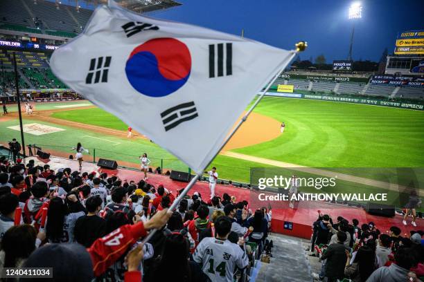 In this picture taken on April 20 a South Korean flag is waved by a fan during play as professional cheerleaders for local baseball team SSG Landers...