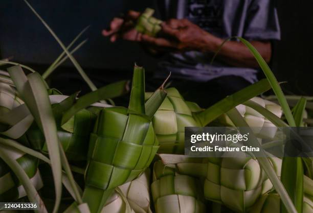 Indonesian vendors weave palm leaves used to make traditional rice cakes known as &#039;Ketupat&#039; in preparation of the upcoming Eid al-Fitr in...