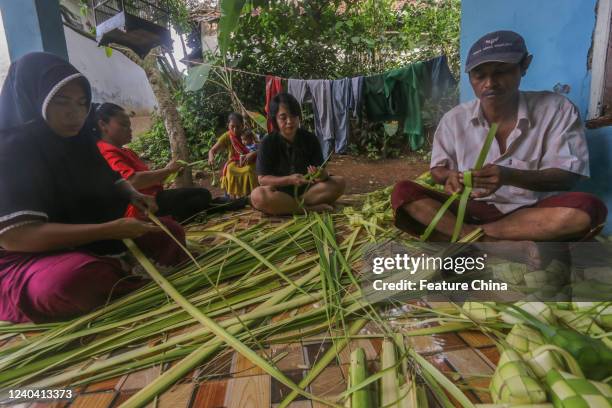 Indonesian vendors weave palm leaves used to make traditional rice cakes known as &#039;Ketupat&#039; in preparation of the upcoming Eid al-Fitr in...