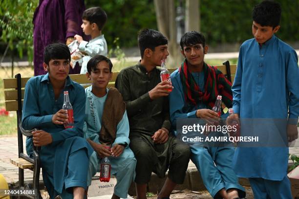 Boys drink a beverage while sitting at the Lake Viewpoint during the Eid al-Fitr festival, which marks the end of their holy fasting month of...