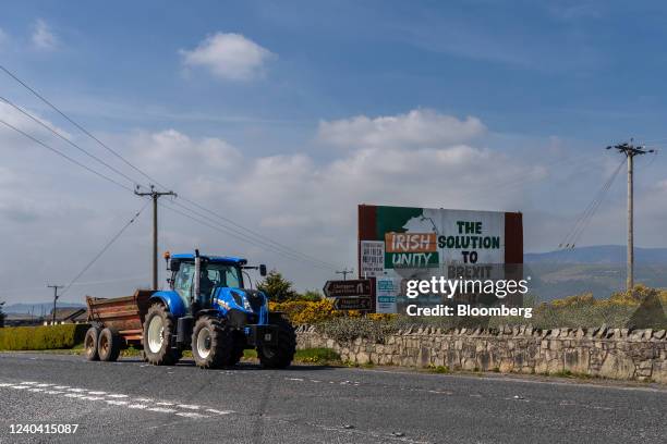 Tractor passes an Irish Unity and Sinn Fein election poster set up on a roadside near an unmarked border crossing near Newry, Northern Ireland, U.K.,...