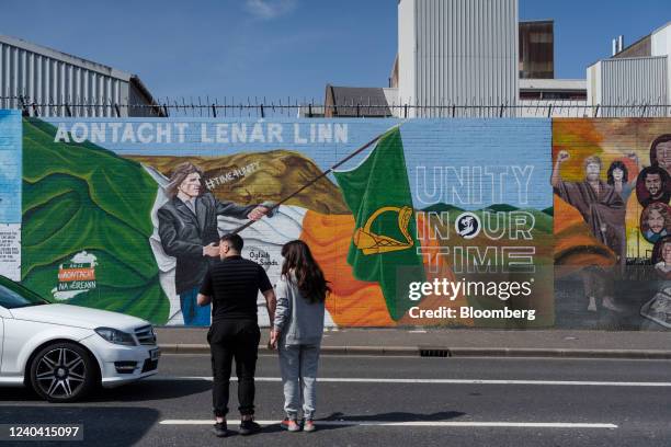 Tourists walk towards an Irish Unity mural in the Falls Road, a prominently Nationalist and Republican area, in West Belfast, Northern Ireland, U.K.,...