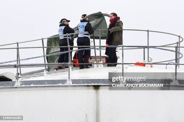 Police Liaison Officers speak to a Just Stop Oil climate activist protesting at the Nustar Clydebank oil terminal in Glasgow on May 3, 2022. -...