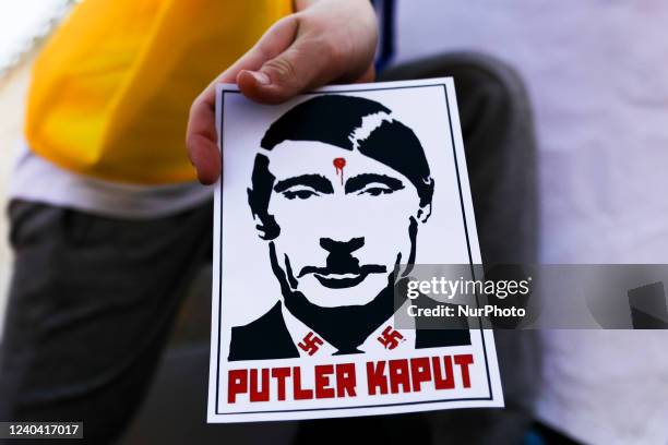 Poster with Vladimir Putin shown as Adolf Hitler and phrase 'Putler Kaput' is seen during a demonstration of solidarity with Ukraine at the Main...