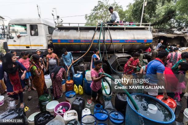 Residents use hoses to collect drinking water from a tanker truck during a hot summer day in New Delhi on May 3, 2022.