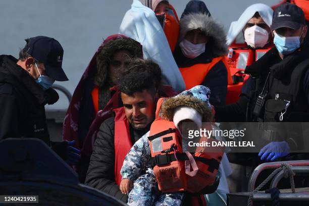 Migrants, picked up at sea while attempting to cross the English Channel, are helped by a member of the UK Border Force to disembark from a boat, in...