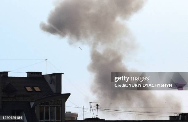 Missile flies over as dark smoke rises during an air strike in the western Ukrainian city of Lviv, on May 3, 2022.