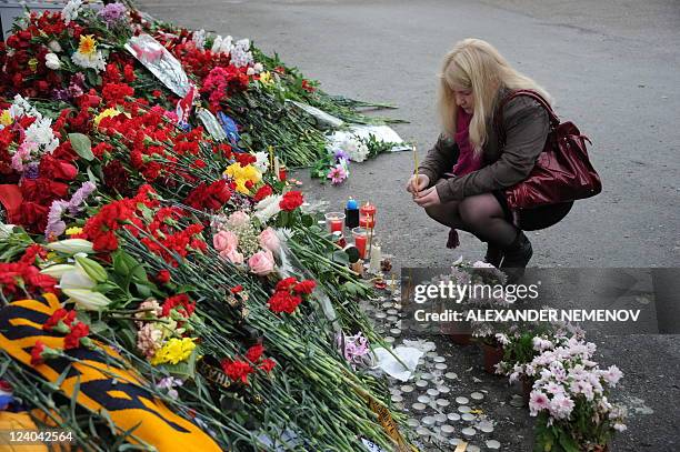 Woman places a candle in front of the Arena-2000 stadium, the home venue of Russian ice hockey team Lokomotiv Yaroslavl in the city of Yaroslavl, 300...