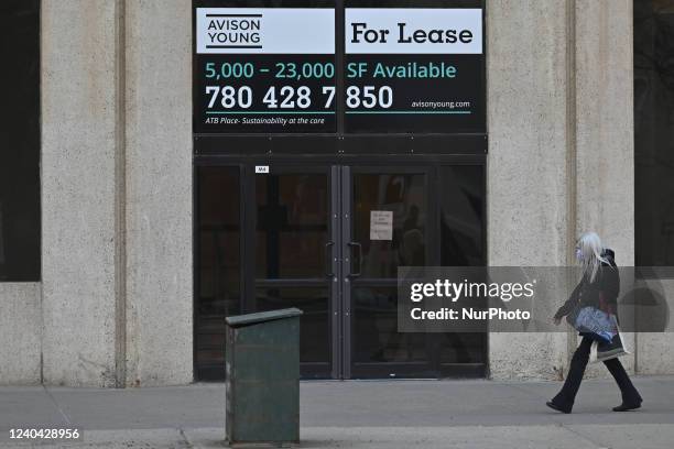 Woman walks past a sign 'For Lease' seen outside a business promisses in downtown Edmonton. On Monday, May 2 in Edmonton, Alberta, Canada.
