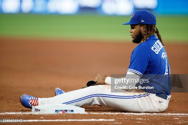 Vladimir Guerrero Jr. #27 of the Toronto Blue Jays sits at first base after missing a tag on Giancarlo Stanton of the New York Yankees following a...