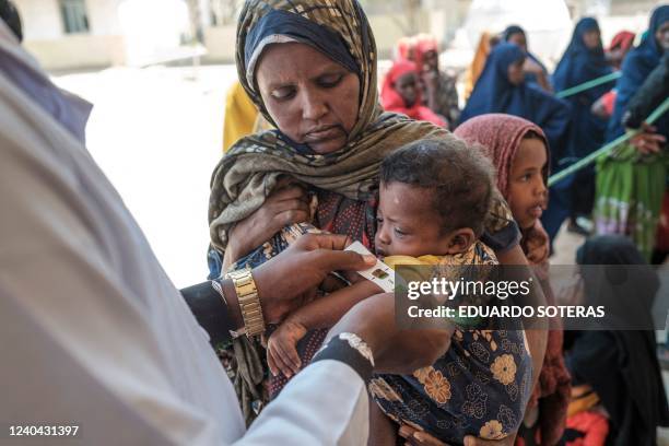 Health personnel measures the arm of an internally displaced child during a food distribution organised by the World Food Program in the village of...